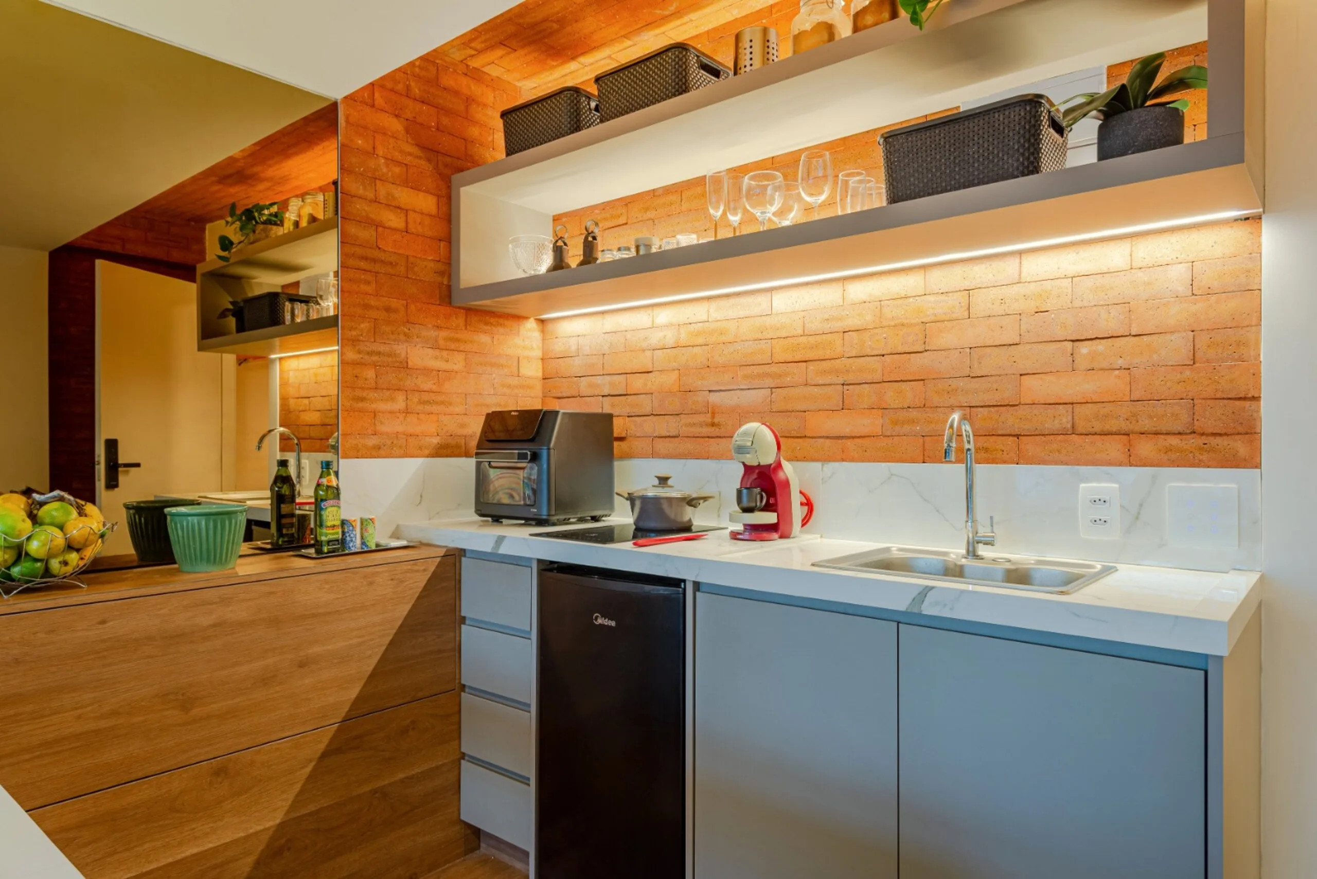 Cozinha completa e integrada equipada com fogão de indução, forno air fryer, frigobar, cafeteira e itens básicos de cozinha.