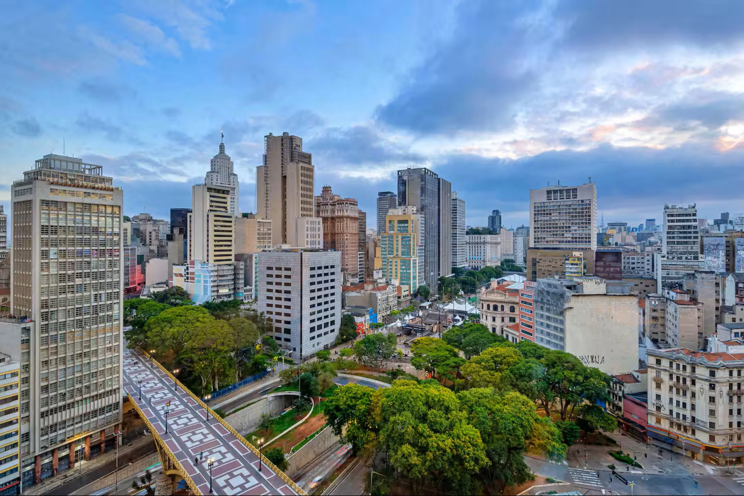 Uma vista ampla do Centro Histórico de São Paulo, com seus prédios icônicos, áreas verdes e vias elevadas, revelando a paisagem urbana vibrante e cheia de contrastes que caracteriza a região.